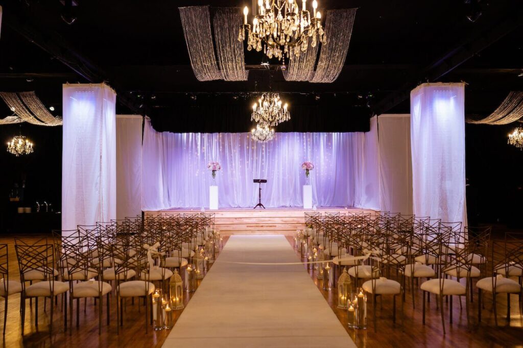 Wedding ceremony setup with gold chairs and white aisle runner at Winston-Salem Millennium Center.