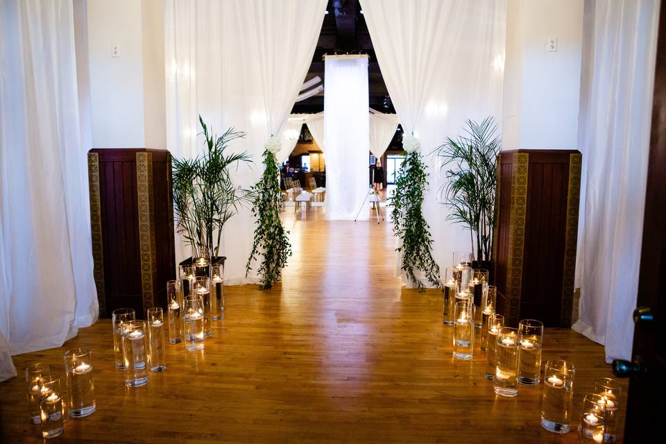 The entrance to the ballroom of Millennium Center decorated in candles and white draping with greenery.